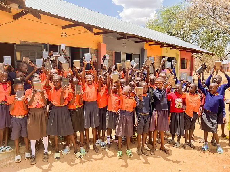 Children celebrating with Bibles outdoors.