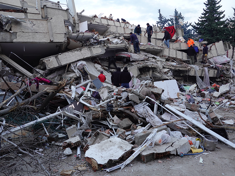 People dig through piles of rubble, searching for survivors and victims.