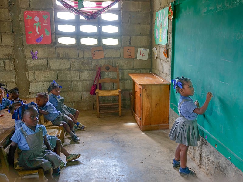 A girl writes on the chalkboard at a Haitian school.