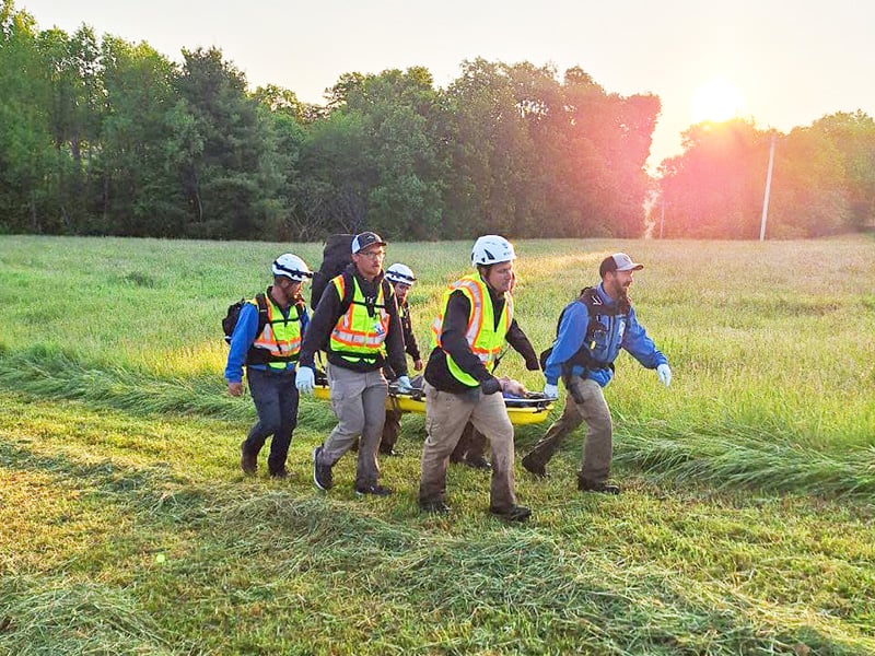 Rescue team carrying stretcher outdoors.