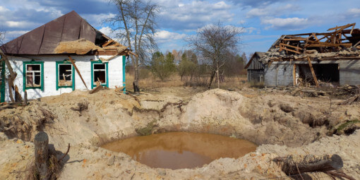 Bomb crater near war damaged home in Ukraine