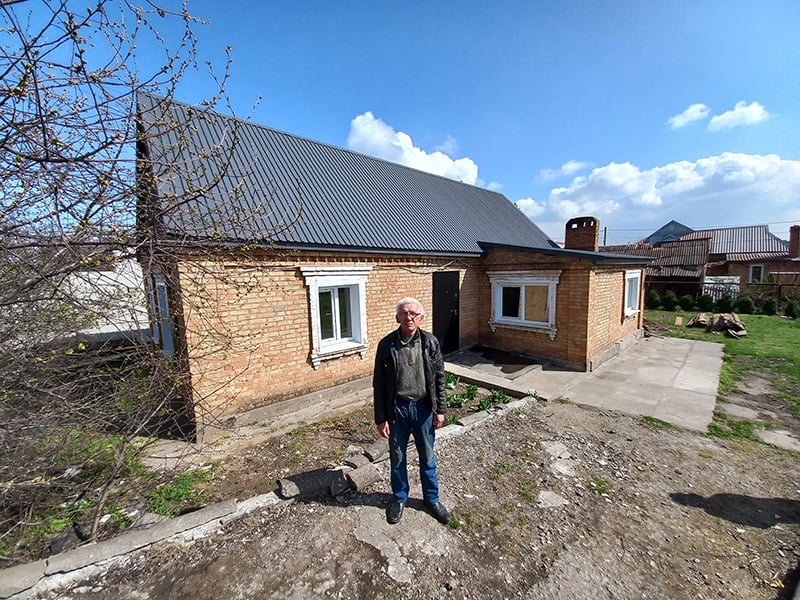 Volodymyr standing in front of fixed house
